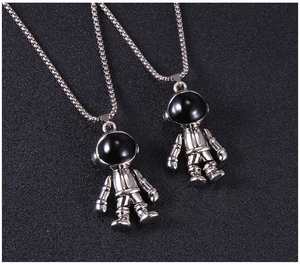 Détail macro de pendentifs astronaute en argent avec visières noires et chaînes box