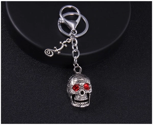 Detail of vintage silver skull keychain with red rhinestone eyes and lizard charm