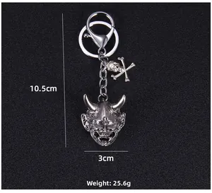 Detail of silver demon mask keychain with skull charm and 10.5cm length measurement
