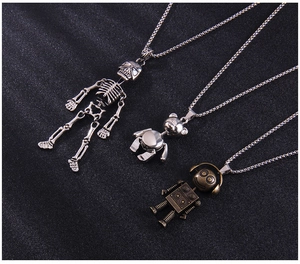 Détail de pendentifs crâne et robot de style punk sur chaîne en alliage sur fond noir