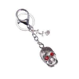 Gothic silver skull keychain with red rhinestone eyes and gecko charm on white background