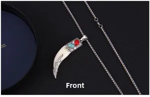 Détail du pendentif dent de loup vintage avec pierre rouge et incrustation turquoise