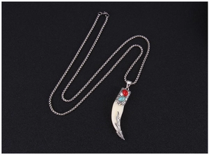 Vue détaillée du pendentif dent de loup tribal avec pierres rouges et turquoise sur chaîne