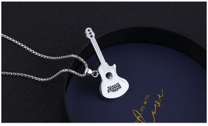 Detail of white guitar pendant with black Rock lettering and silver chain on blue display