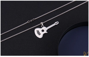 Detail of artistic guitar pendant necklace with engraved lettering on black texture