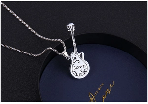 Macro detail of silver guitar pendant with LOVE engraving and intricate floral vine patterns