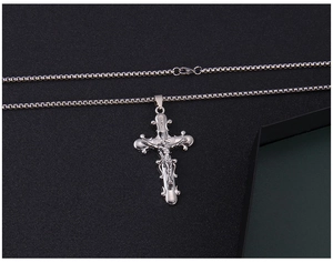 Vue détaillée du pendentif crucifix en acier argenté sur une chaîne à mailles box