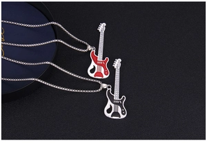Close-up of red and black enamel guitar pendants on bead chains over a dark textured surface