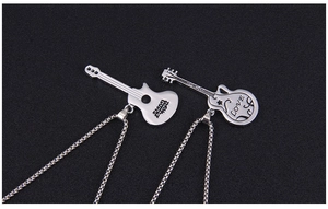 Close-up of silver guitar necklaces for couples with LOVE engraving on a dark background
