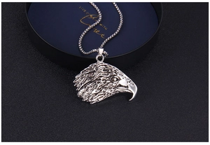 Vue macro du pendentif tête d'aigle avec détails de plumes et chaîne à billes argent