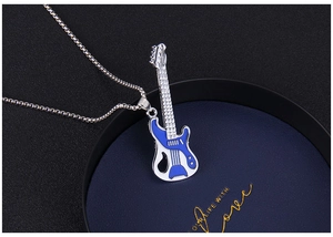 Detailed close-up of a blue and white guitar pendant necklace on dark blue velvet