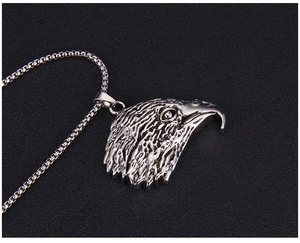 Détails en relief du pendentif tête d'aigle vintage en acier inoxydable sur fond noir texturé