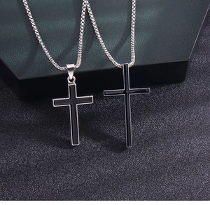 Close-up of two distinct black enamel cross pendants with silver stainless steel chains