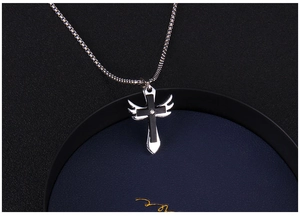 Détail d'ailes d'ange argentées et pendentif croix noire avec pierre sur chaîne box