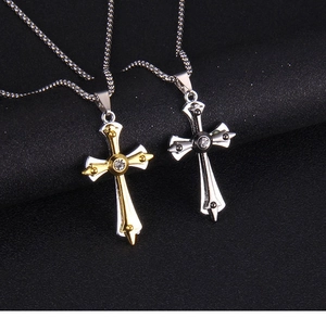 Dettaglio macro di pendenti a croce gotica con strass incastonati e finiture metalliche bicolore