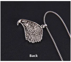 Vue arrière macro du pendentif tête d'aigle argenté avec gravure de plumes sur chaîne box