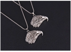 Gros plan sur deux pendentifs tête d'aigle en acier avec texture de plumes détaillée
