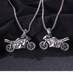 Close-up of two vintage motorcycle pendants on long chains over a black textured surface