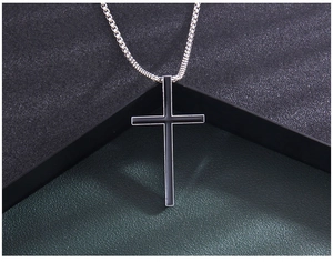 Detail of a vintage black enamel cross pendant with a polished silver stainless steel box chain