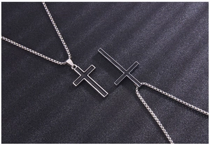Detail of two black oil-drop cross pendants on polished steel ball chains