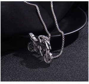 Detail of vintage punk motorcycle pendant on silver box chain against black background