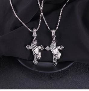 Detail of gothic stainless steel cross pendant featuring praying hands on black silk