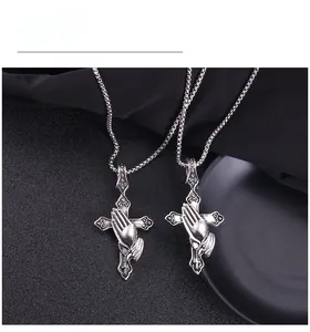 Detailed view of vintage silver punk cross and praying hands pendant on black silk