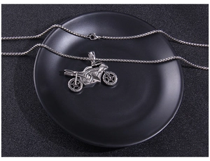 Close-up of a silver motorcycle pendant necklace showing detailed engine and wheels