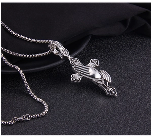Detailed close-up of retro punk style praying hands and cross stainless steel pendant