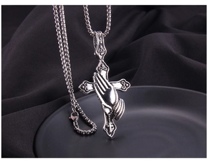 Close-up of punk style stainless steel prayer hands on a cross pendant with box chain