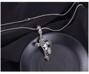 Macro view of vintage cross and praying hands pendant with antique black texture