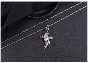 Macro view of punk style stainless steel praying hands and cross pendant on bead chain
