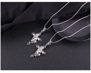 Close-up of punk style stainless steel cross and praying hands necklace in retro silver