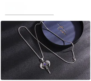 Detailed shot of an angel wing cross necklace with a blue gemstone on dark texture