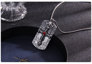 Gros plan du collier croix argenté vintage avec gemme rouge et détails en relief