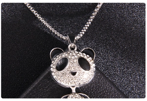 Detailed macro shot of a cute panda pendant with sparkling crystals on black leather background