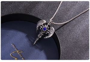 Macro shot of silver titanium steel cross necklace with wings and blue gemstone pendant