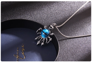 Detail of blue evil eye pendant with skull and claw elements on a silver metal chain