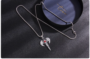 Macro shot of silver angel wing cross pendant with a red gemstone on a luxury gift box