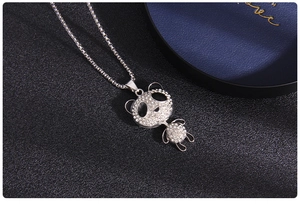 Close-up of a panda pendant necklace with sparkling crystals on a black leather background