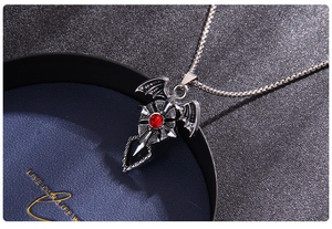 Gros plan d'un pendentif gothique croix chauve-souris avec pierre rouge et détails argentés