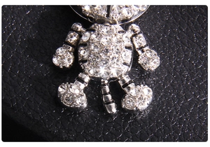 Détail macro d'un pendentif tigre en argent orné de strass sur fond de cuir noir texturé