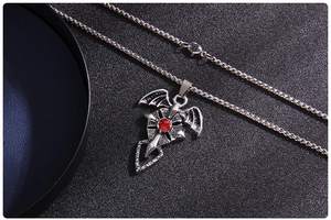 Détail macro d'un pendentif croix chauve-souris gothique avec gemme rouge et chaîne