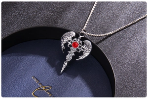 Macro detail of gothic cross pendant with red gemstone and silver angel wings