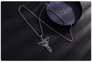Detailed macro view of punk style double dragon cross necklace with red gemstone and silver chain