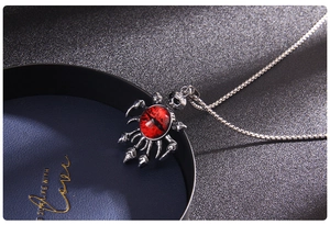 Macro detail of gothic skull spider claw pendant with a red evil eye resin stone