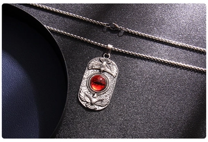 Macro detail of gothic stainless steel necklace with red evil eye and eagle relief