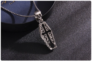 Macro shot of gothic coffin pendant with skull and cross on vintage steel chain