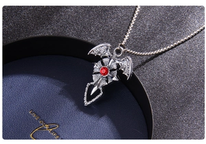 Détail du collier croix chauve-souris argentée avec gemme rouge sur coffret cadeau
