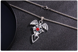 Vue détaillée du collier croix gothique avec ailes de chauve-souris et pierre rouge